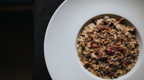 Immagini che emozionano: appartamenti Presulis a Fiè Risotto con funghi e fiori secchi su piatto bianco