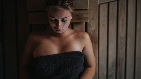 Immagini che emozionano: appartamenti Presulis a Fiè Donna rilassata in sauna con asciugamano avvolto, occhi chiusi