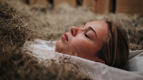 Immagini che emozionano: appartamenti Presulis a Fiè Donna sdraiata con gli occhi chiusi nel fieno in una stalla di legno