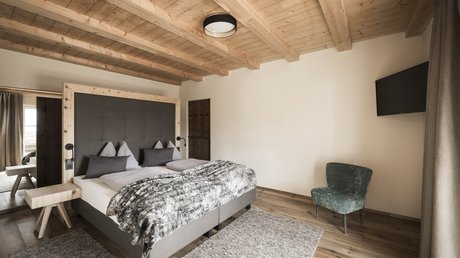 Immagini che emozionano: appartamenti Presulis a Fiè Camera da letto accogliente con soffitto in legno, letto matrimoniale e TV