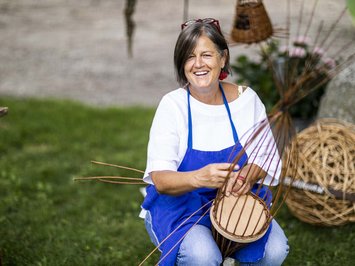 Seiser Alm Balance: active & healthy throughout spring Woman smiling while weaving a basket outdoors