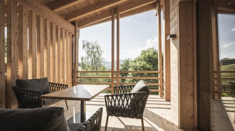 Immagini che emozionano: appartamenti Presulis a Fiè Veranda in legno con sedie e tavolo vista foresta verde e montagne