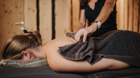 Immagini che emozionano: appartamenti Presulis a Fiè Donna riceve massaggio alla schiena in un ambiente spa rilassante