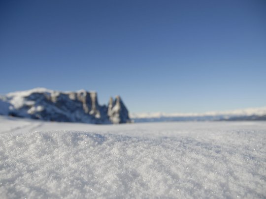 Presulis: Ihre Luxus-Ferienwohnung in Völs am Schlern Nahaufnahme von glitzerndem Schnee im Vordergrund mit Berglandschaft im Hintergrund