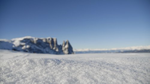 Ankommen und durchatmen: Urlaub in Völs am Schlern Nahaufnahme von glitzerndem Schnee im Vordergrund mit Berglandschaft im Hintergrund
