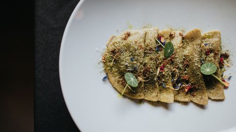 Immagini che emozionano: appartamenti Presulis a Fiè Ravioli ripieni su piatto bianco con foglie verdi e spezie