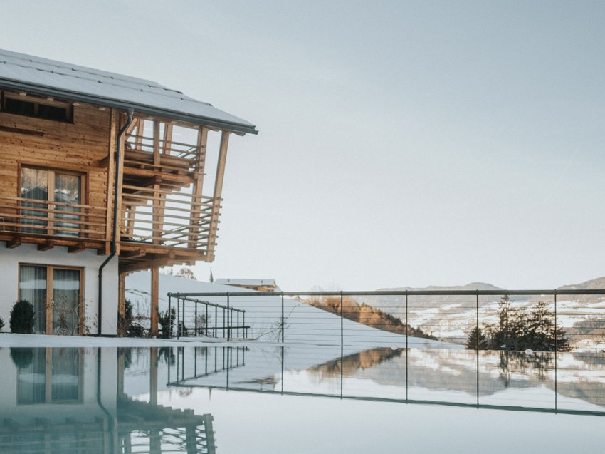 Ihre Luxus-Ferienwohnung in Völs am Schlern mit Pool Holzhaus mit Balkon und Pool vor verschneiten Bergen