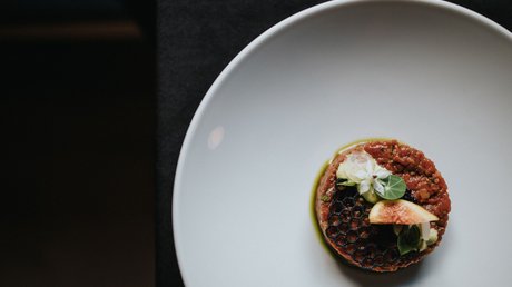 Immagini che emozionano: appartamenti Presulis a Fiè Piatto gourmet artistico con fiore e fico su piatto bianco