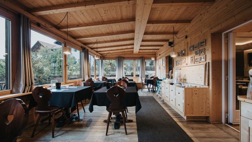Ankommen und durchatmen: Urlaub in Völs am Schlern Gemütliches Restaurant mit Holzmöbeln und schwarzen Tischdecken