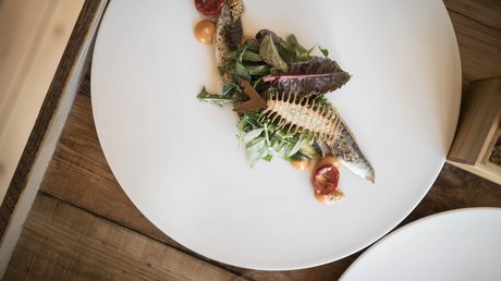 Immagini che emozionano: appartamenti Presulis a Fiè Piatto gourmet con pesce, insalata e decorazione a tema lisca di pesce