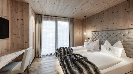 Immagini che emozionano: appartamenti Presulis a Fiè Camera accogliente con pareti in legno, due letti e coperte pelose