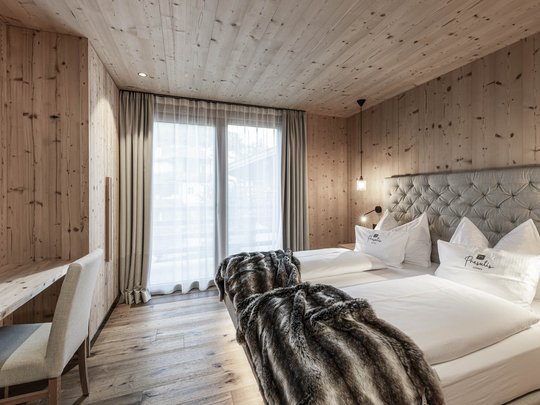 Presulis: Ihre Luxus-Ferienwohnung in Völs am Schlern Gemütliches Schlafzimmer mit Holzwänden, zwei Betten und flauschigen Decken
