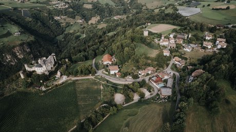 Heartfelt snapshots: the Presulis apartments in Völs Aerial view of a village with a castle, surrounding fields, and forests