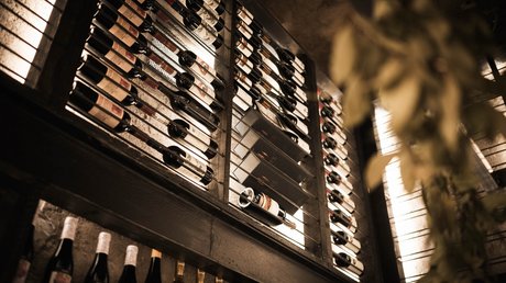 Immagini che emozionano: appartamenti Presulis a Fiè Bottiglie di vino in una scaffalatura illuminata in una cantina