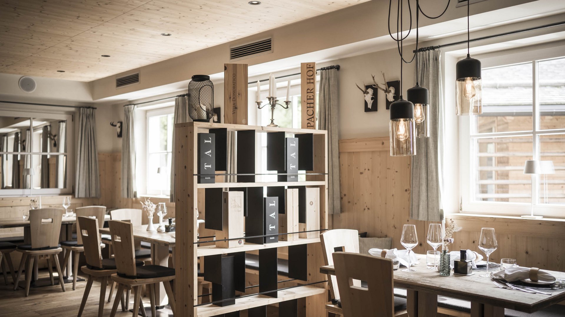 Purer Genuss in unserem Restaurant in Völs am Schlern Gemütliches Restaurant mit Holzmöbeln und Weinregal in natürlichem Licht
