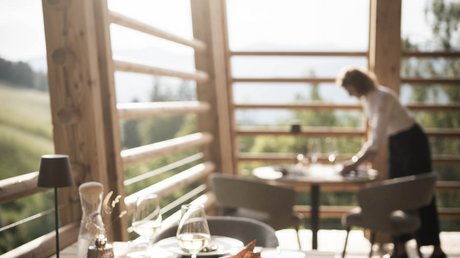 Immagini che emozionano: appartamenti Presulis a Fiè Tavolo in legno apparecchiato in terrazza con cameriera sullo sfondo