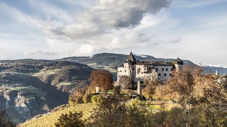 Heartfelt snapshots: the Presulis apartments in Völs Castle on a hill in autumnal mountain landscape with cloudy sky