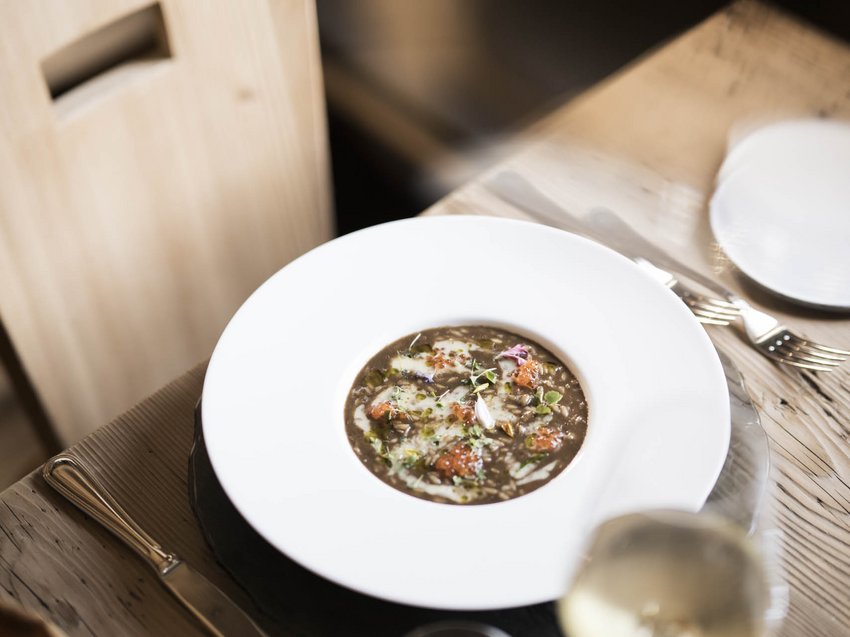 Gusto e benessere negli appartamenti con spa in montagna Tavola apparecchiata con piatto di zuppa e bicchiere di vino bianco