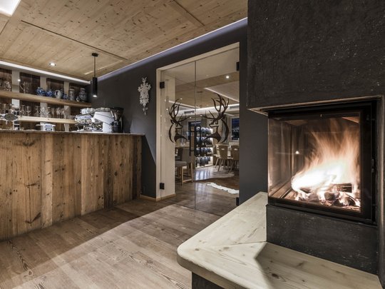 Presulis: Ihre Luxus-Ferienwohnung in Völs am Schlern Gemütliche Bar mit Holztheke und Kaminfeuer in modernem Restaurant