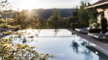 Immagini che emozionano: appartamenti Presulis a Fiè Tramonto su una piscina tranquilla con terrazza e piante in primo piano