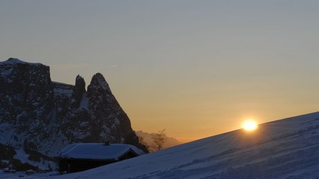 Immagini che emozionano: appartamenti Presulis a Fiè Tramonto su collina innevata con montagne e baita