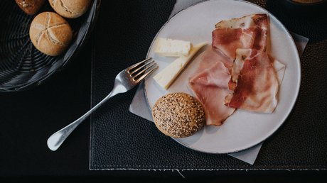 Immagini che emozionano: appartamenti Presulis a Fiè Piatto di colazione con prosciutto, formaggio, panini e caffè su tavolo scuro
