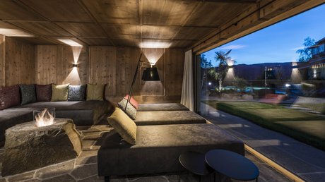 Immagini che emozionano: appartamenti Presulis a Fiè Lounge accogliente con camino e vista sul giardino al crepuscolo