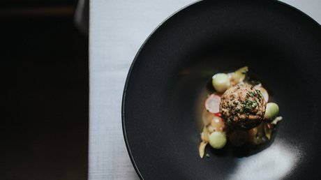 Immagini che emozionano: appartamenti Presulis a Fiè Piatto artistico su piatto nero con erbe e verdure.