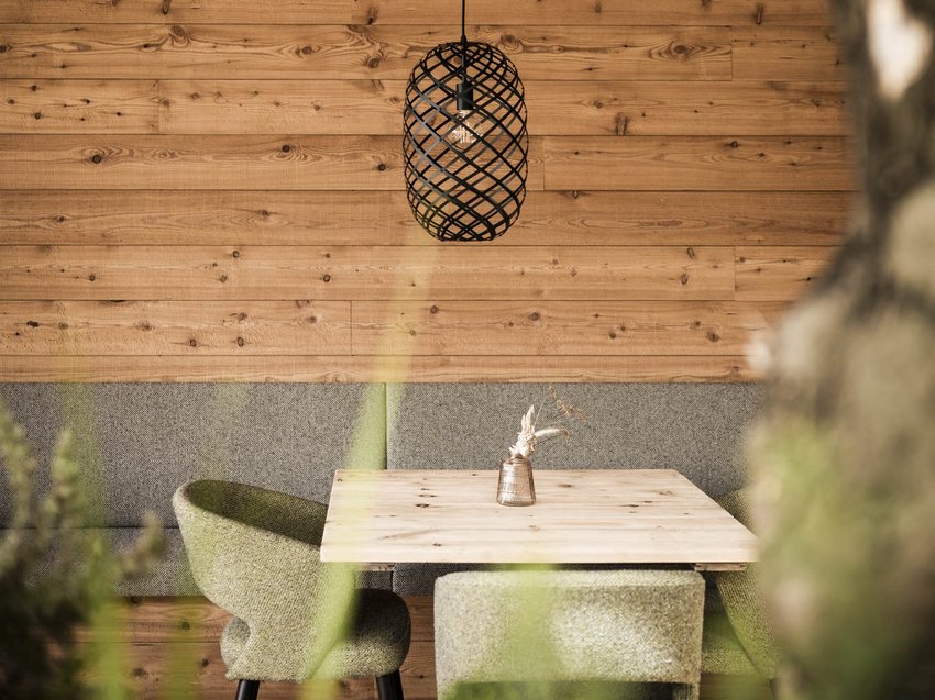 Nachhaltigkeit Gemütlicher Sitzbereich mit Holztisch, grünen Stühlen und Wandleuchte