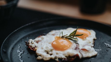 Immagini che emozionano: appartamenti Presulis a Fiè Uova fritte su un piatto nero con un rametto di rosmarino