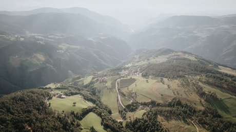 Heartfelt snapshots: the Presulis apartments in Völs Aerial view of hilly landscape with forests and villages in the valley