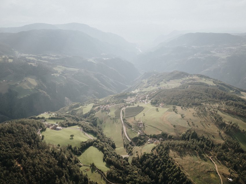 Presulis Slow hideaway: Wanderurlaub in den Dolomiten Luftaufnahme von hügeliger Landschaft mit Wäldern und Dörfern im Tal