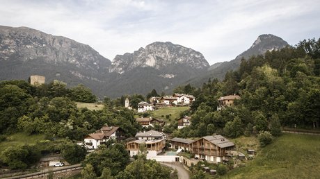 Bilder, die begeistern: Presulis Hideaway Apartments & Restaurant in Völs Dorf mit Häusern und Bergen im Hintergrund unter bewölktem Himmel