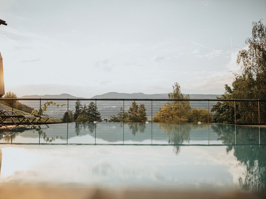 Sport e relax in appartamenti all’Alpe di Siusi con piscina Piscina a sfioro con vista sulle montagne al tramonto
