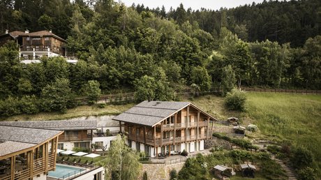 Immagini che emozionano: appartamenti Presulis a Fiè Casa in legno e piscina in paesaggio montano verde con foresta sullo sfondo