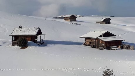 Immagini che emozionano: appartamenti Presulis a Fiè Paesaggio innevato con diverse baite di legno e impronte sulla neve