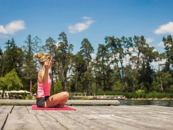 Seiser Alm Balance: active & healthy throughout spring Woman doing yoga on wooden dock by lake on a sunny day