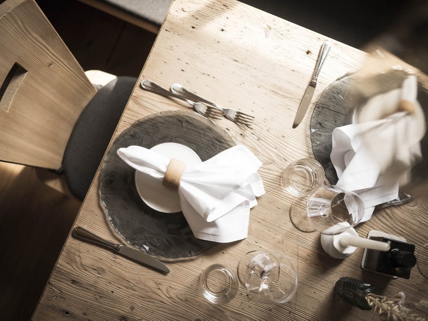 Genuss, der beflügelt: die Kulinarik im Presulis Rustikaler Holztisch mit elegant gedecktem Platz und weißen Servietten